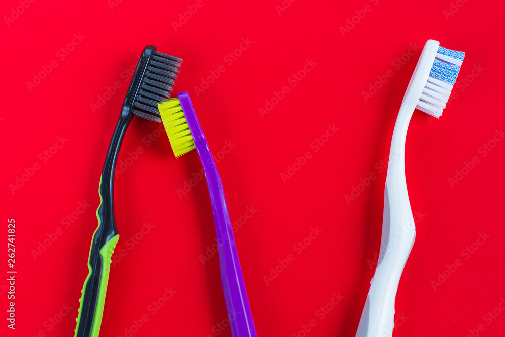 multicolored toothbrushes on a red background multicolored toothbrushes on a red background