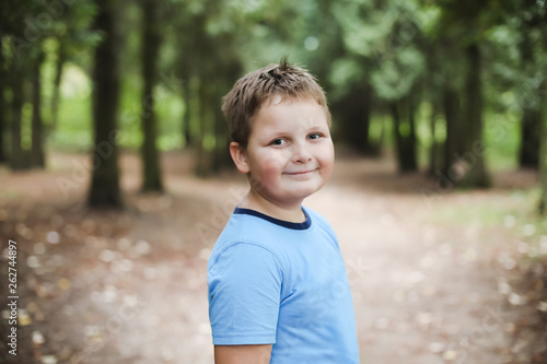 Portrait of a cute smiling boy in sunny autumn day. Portrait of young boy in nature, park or outdoors.