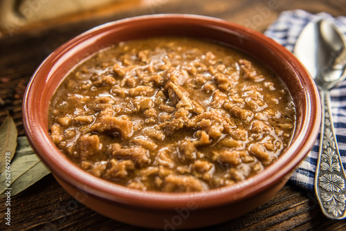 tripe stew sauce in brown ceramic pot on a wood table 