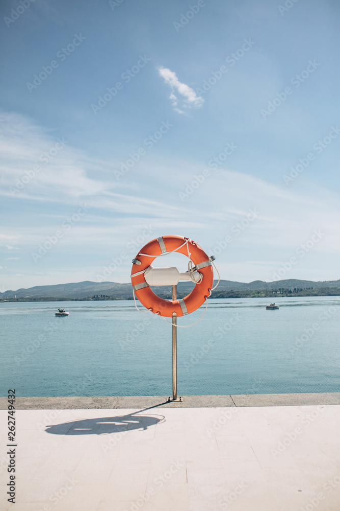Lifebuoy on the pier or port on the background of the sea on a summer sunny day.