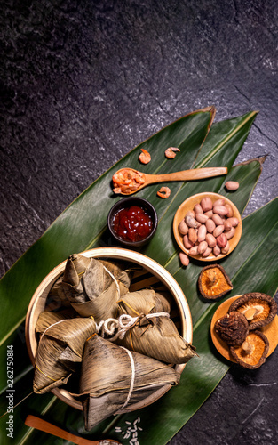 Close up, copy space, top view, flat lay. Famous asian chinese tasty handmade food in duan wu event, steamed rice dumplings shaped like pyramidal ingredient on black slate photo