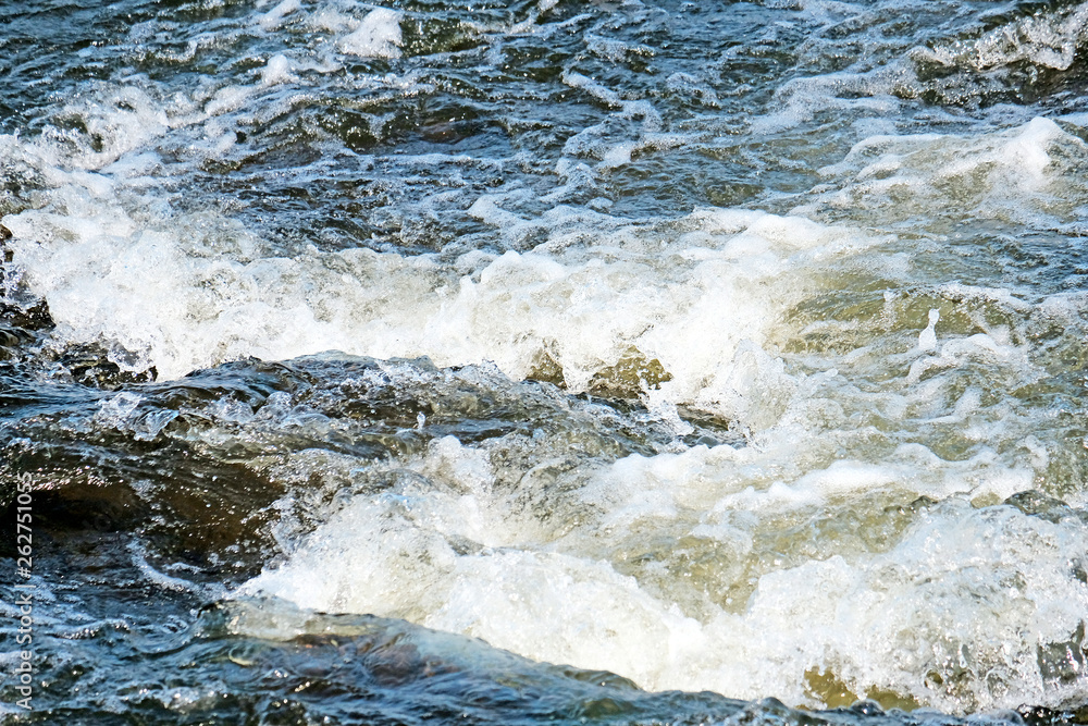 A powerful whirlpool is formed on the surface of the green and blue waters of the river. Foam on the water surface close-up. Spring flood. A powerful whirlpool is formed on the surface of the green and blue waters of the river. Foam on the water surface close-up. Spring flood.