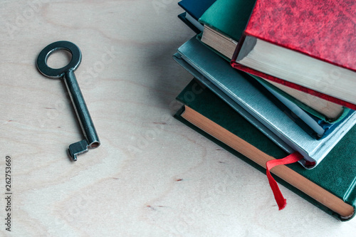 Key and stack of books on wooden background. Metaphor - key to knowledge photo