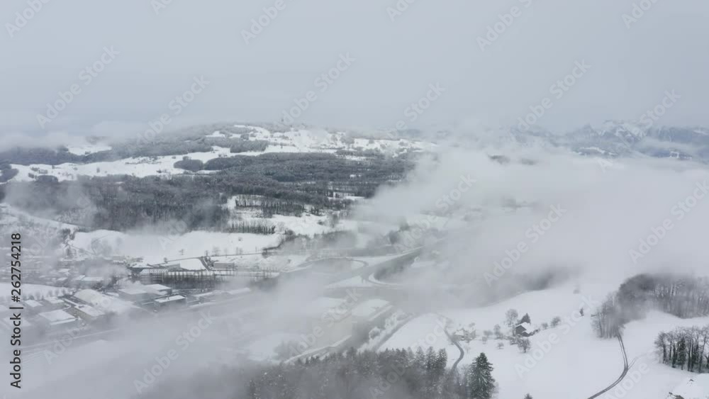 Aerial over snowy and foggy industrial area with hill and forests in the background, Switzerland Aerial over snowy and foggy industrial area with hill and forests in the background, Switzerland