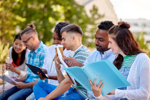 education and people concept - group of happy students with notebooks, tablet computer and takeaway drinks learning outdoors