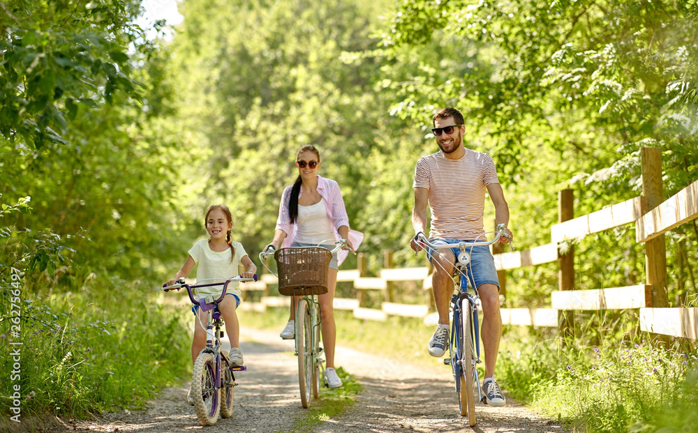 family, leisure and people concept - happy mother, father and little daughter riding bicycles in summer park family, leisure and people concept - happy mother, father and little daughter riding bicycles in summer park