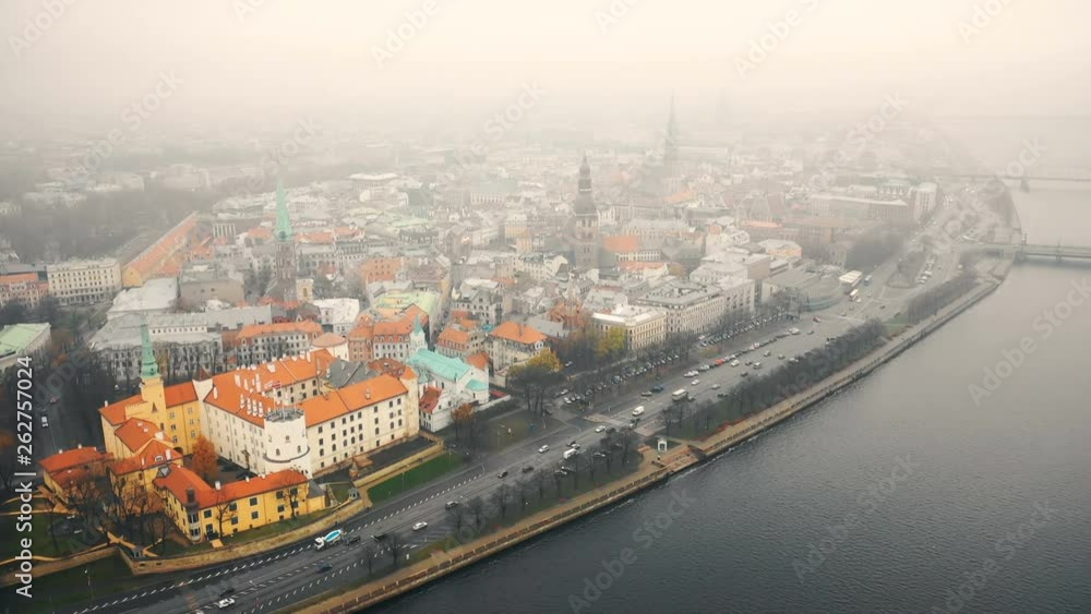 Amazing aerial cityscape panorama of Riga old town and car traffic along river Daugava under fog on cloudy autumn day.