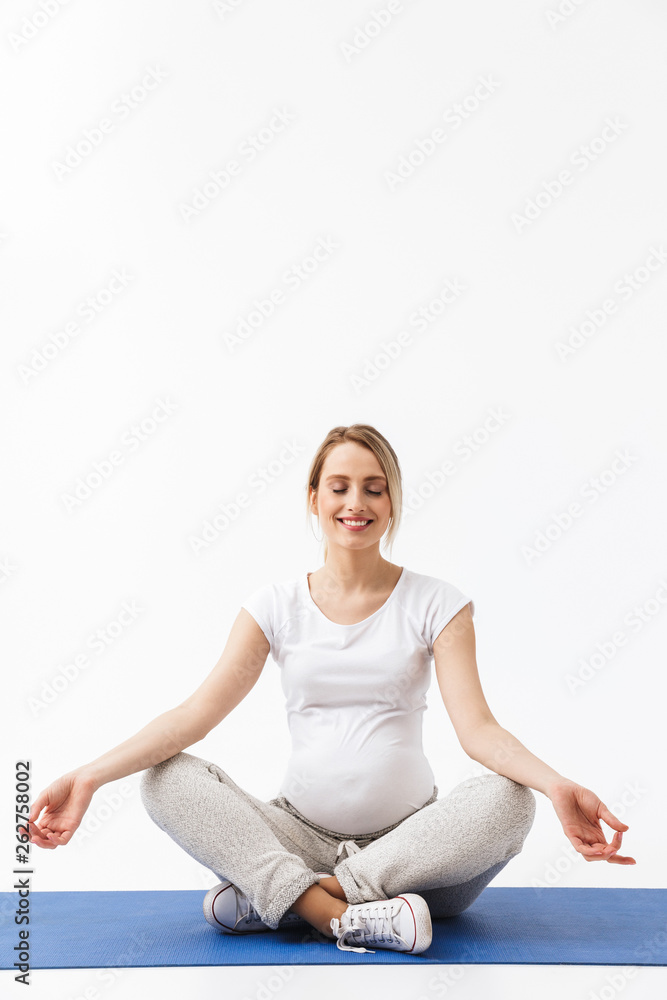 Pregnant yoga fitness woman posing isolated over white wall background make exercises.