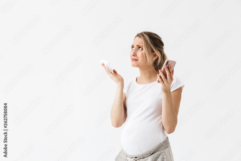 Displeased young pregnant woman posing isolated over white wall background talking by phone. Displeased young pregnant woman posing isolated over white wall background talking by phone.