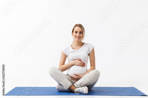 Pregnant yoga fitness woman posing isolated over white wall background make exercises.