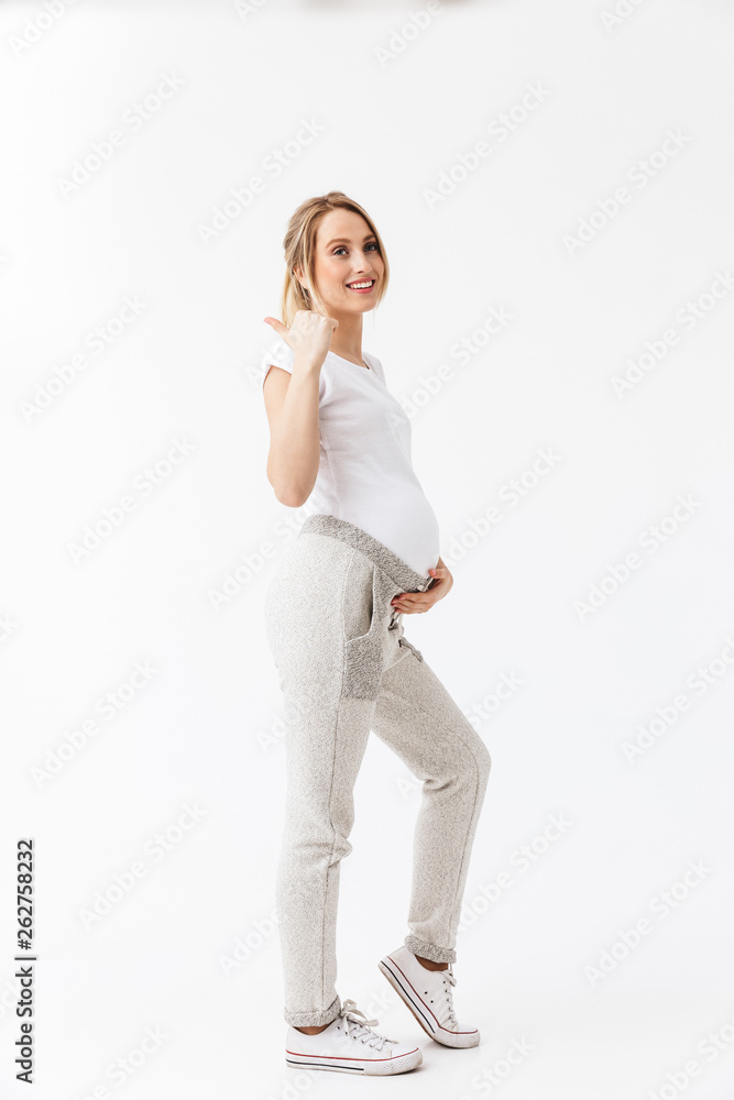 Beautiful young pregnant woman posing isolated over white wall background. Beautiful young pregnant woman posing isolated over white wall background.