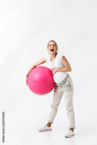 Beautiful young pregnant yoga fitness woman posing isolated over white wall background make exercises with ball.