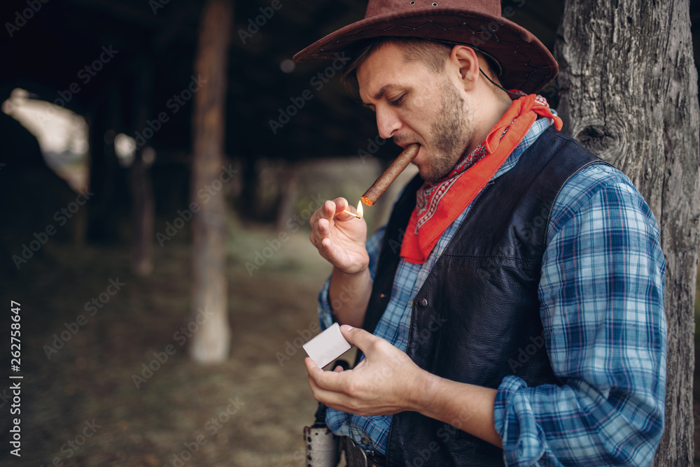 Brutal cowboy lights a cigar with matches