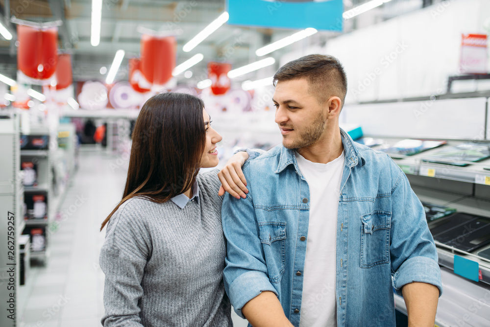 Couple looking on shelf with electric ovens Couple looking on shelf with electric ovens