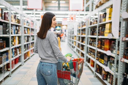 Woman with cart in alcohol drinks department photo
