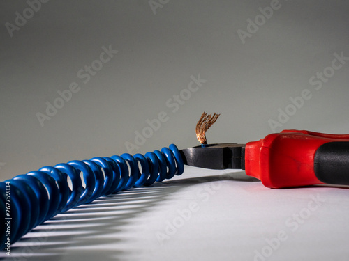 Close up of red pliers and blue twisted wire on white background.Pliers cutting cable