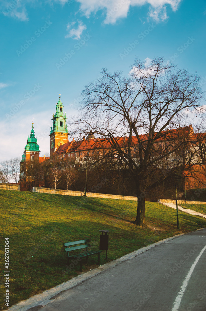 Obraz premium Krakow Wawel Castle at sunset at the end of February, calm warm pleasant weather. Embankment on the Vistula River.