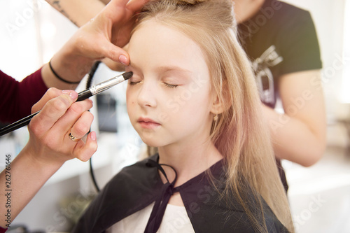 Fotografie Close up of a portrait of a little girl having make-up applied by a makeup artist