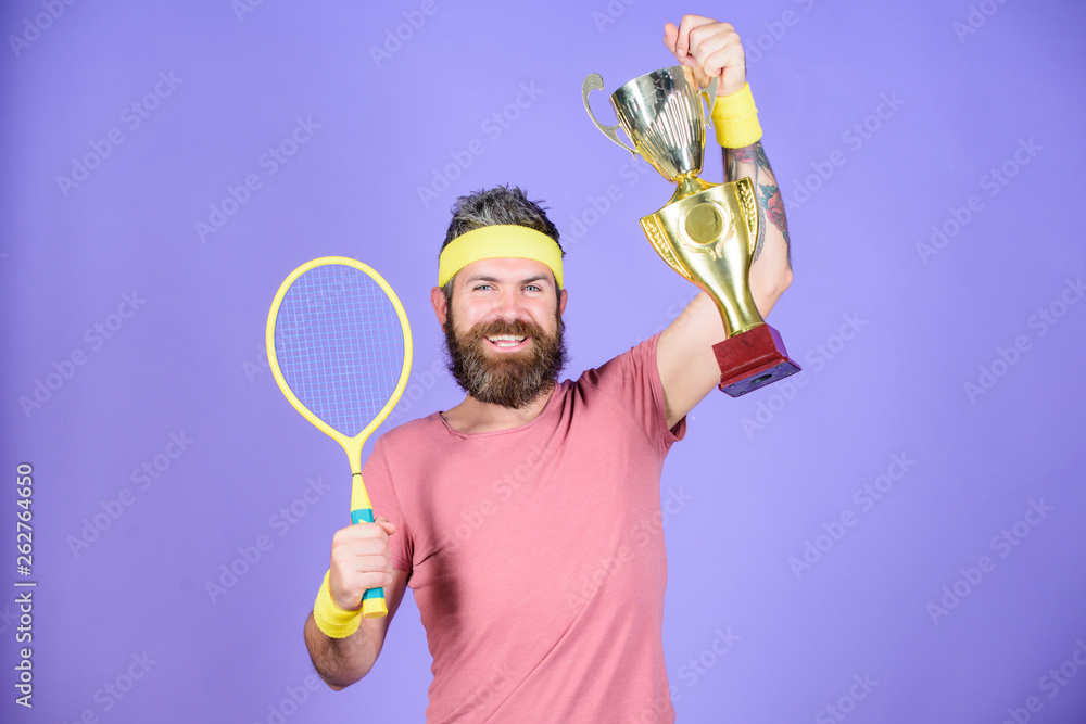 Man bearded hipster wear sport outfit. Success and achievement. Win tennis game. Tennis match winner. Achieved top. Tennis player win championship. Athlete hold tennis racket and golden goblet Man bearded hipster wear sport outfit. Success and achievement. Win tennis game. Tennis match winner. Achieved top. Tennis player win championship. Athlete hold tennis racket and golden goblet