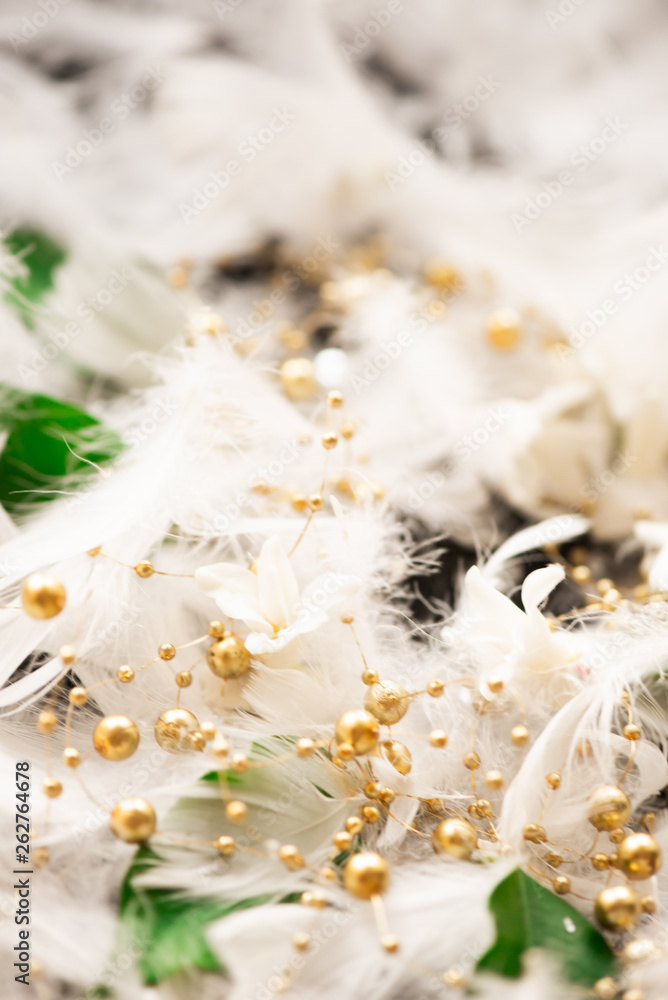 Delicate white feathers green leaves golden beads cosmetics background