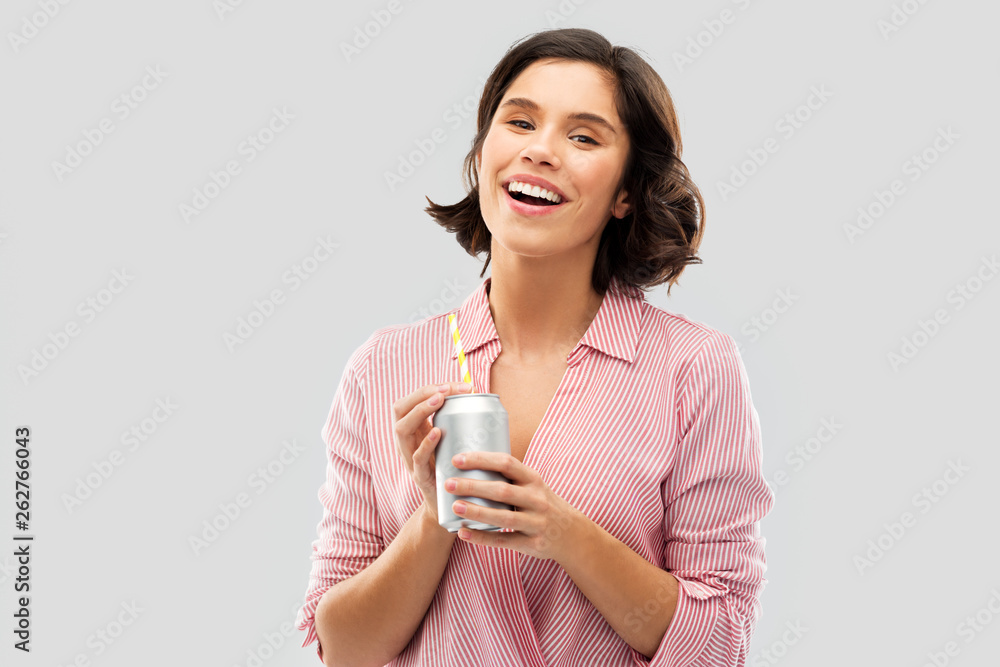 fashion, style and people concept - happy smiling young woman in striped shirt drinking soda from can with paper straw over grey background fashion, style and people concept - happy smiling young woman in striped shirt drinking soda from can with paper straw over grey background