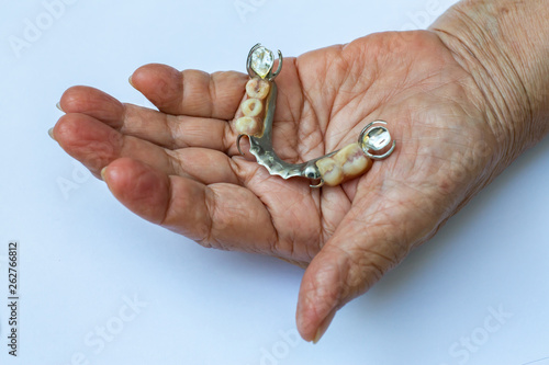 Senior woman's hand holding Artificial teeth, Acrylic and Vitallium metal, On white background, Stomatology & False Dentures set concept, Close up & Macro shot