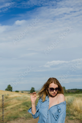 Portrait of beautiful young woman in stylish clothes posing on field
