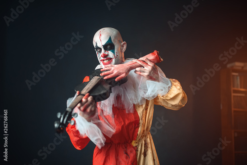 Bloody clown plays the violin with a human hand