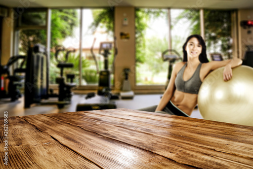 Desk of free space for your decoration and slim young woman in gym interior. 