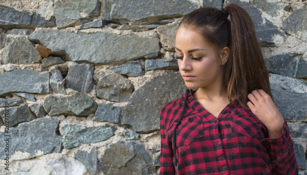 Portrait of beautiful young woman in red shirt and jeans posing outdoor Portrait of beautiful young woman in red shirt and jeans posing outdoor