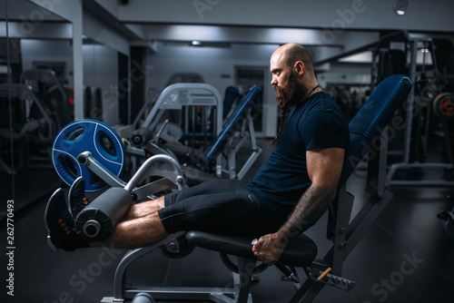 Muscular athlete trains legs on exercise machine