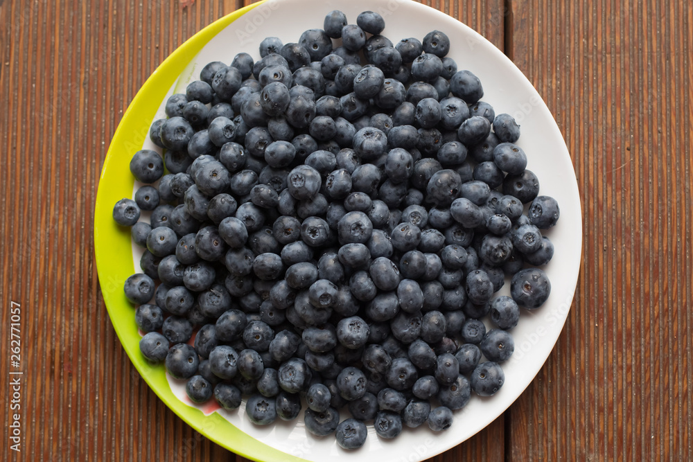 fresh blueberries closeup with dew drops on a plate on a wooden background fresh blueberries closeup with dew drops on a plate on a wooden background