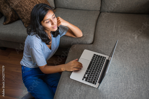 Young indian woman using computer mobile phone at home