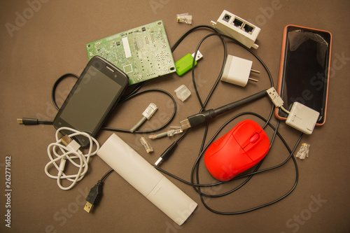 Electric waste. Reduce reuse recycle concept. Colorful electric waste - circuit board, cell phones, battery charger, USB on a brown background. Top view