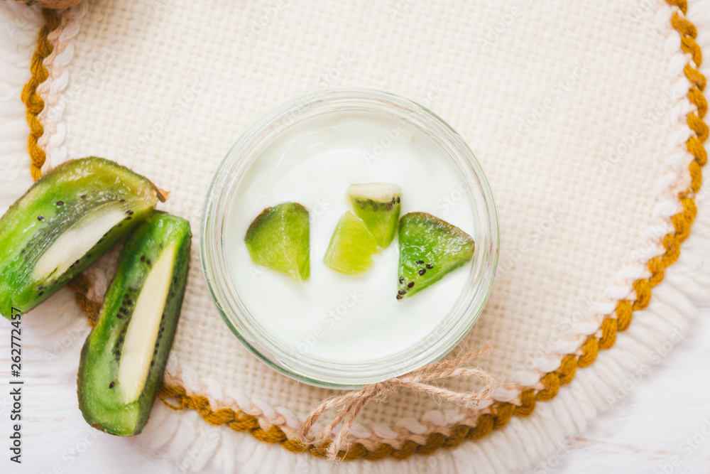 Yogurt with kiwi slices on a wooden white background. Yogurt with kiwi slices on a wooden white background.