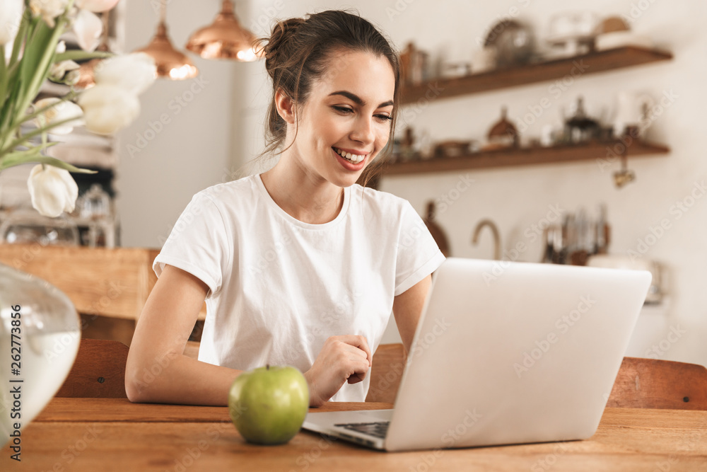 Beautiful young student girl with apple indoors using laptop computer. Beautiful young student girl with apple indoors using laptop computer.