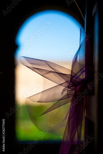 Backlit view of a delicate lilac colored textile wedding decoration, romance and marriage concept.