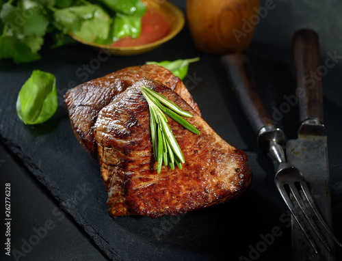 grilled  beef steak on black slate with spices. photo