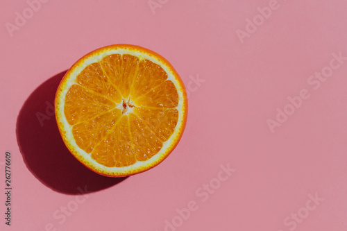 Fresh cutted orange on a pastel pink background closeup at the left side of the table photo