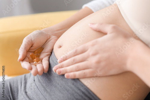 Pregnant woman with vitamins at home, closeup