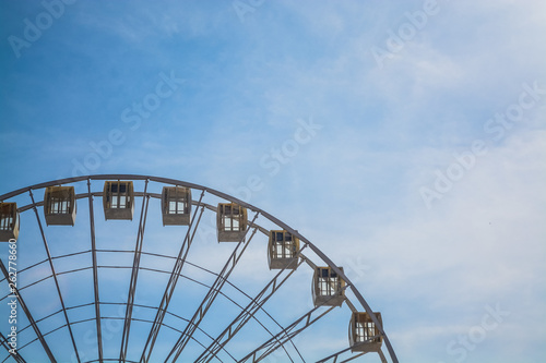 Big wheel against the background of the blue sky and an old city architecture Kiev, Ukraine. Amusement park. Area. © Vlada