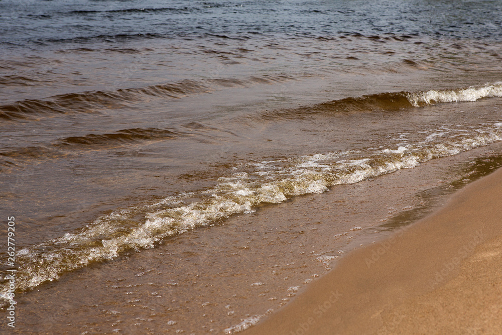 Waves with foam on a sunny summer day. Sandy beach Waves with foam on a sunny summer day. Sandy beach