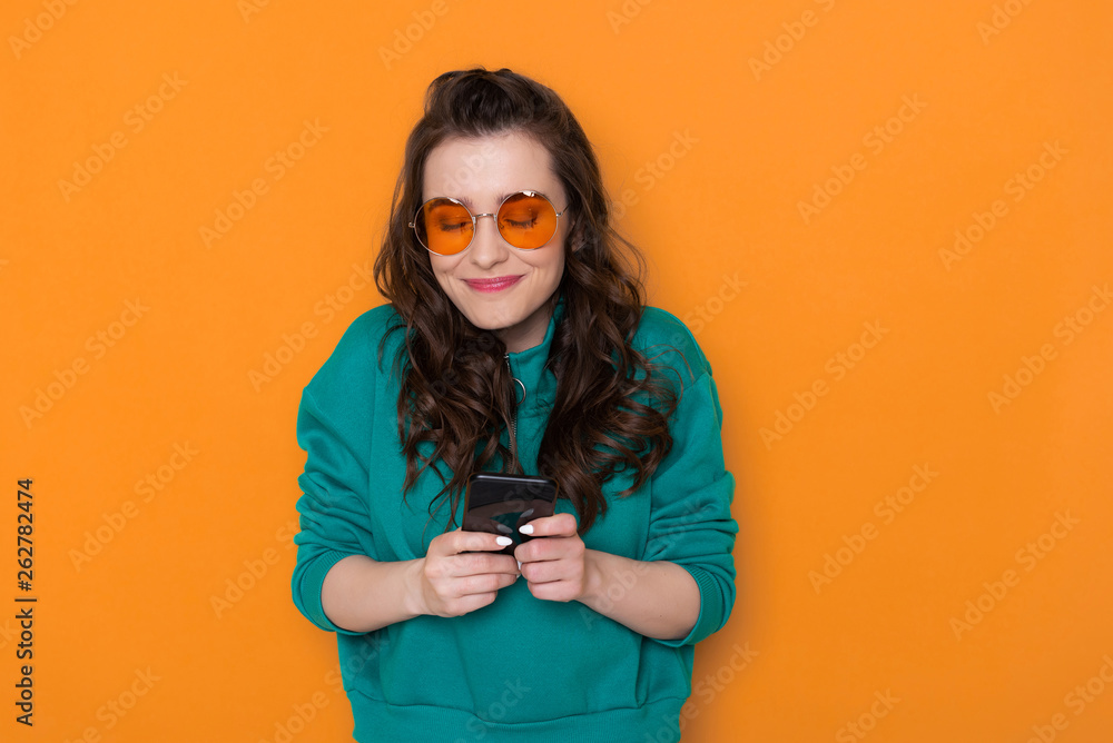 Half length of smiling fashionable Caucasian girl typing sms on smartphone Half length of smiling fashionable Caucasian girl typing sms on smartphone