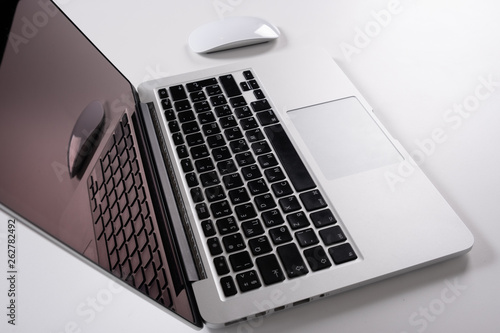 Laptop on a light table with a mouse and a telephone