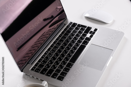 Laptop on a light table with a mouse and a telephone