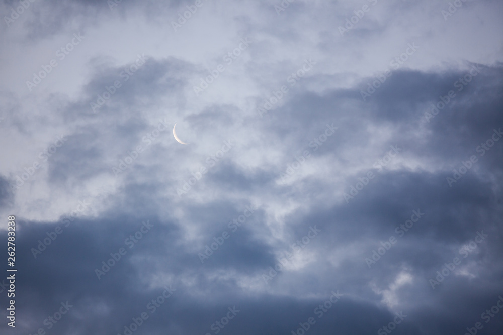 Moon crescent in sky behind clouds Moon crescent in sky behind clouds