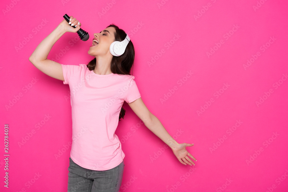 Cropped photo of Caucasian female singer in headphones and holding microphone Cropped photo of Caucasian female singer in headphones and holding microphone