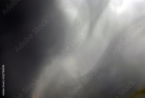 Stream of thick smoke on a dark background, abstraction.