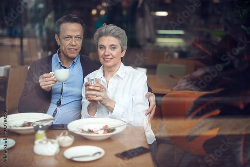 Happy elegant aged couple meeting in cafe