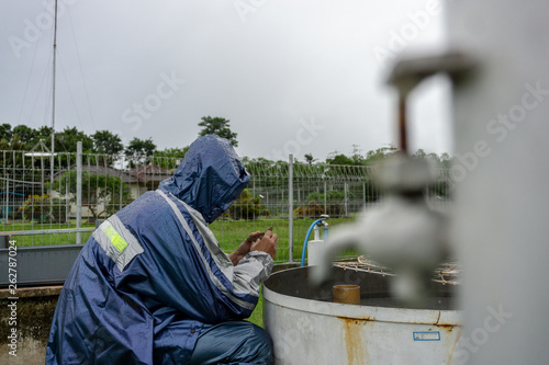 BALI/INDONESIA-DECEMBER 21 2017: A meteorological observer checks the water thermometer to make sure the evaporation rate on that rainy day